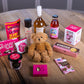 En smukt præsenteret  af produkter til en gavekurv til en pige-barnedåb, fyldt med lyserøde produkter og en kær bamse